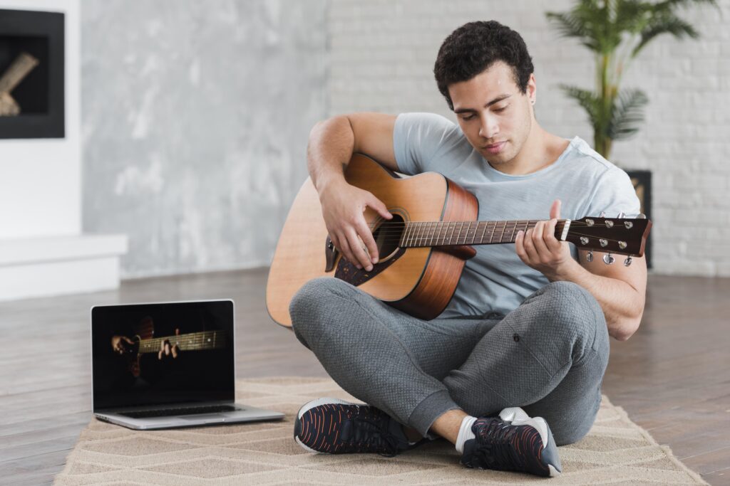 man-sitting-floor-learning-how-play-guitar